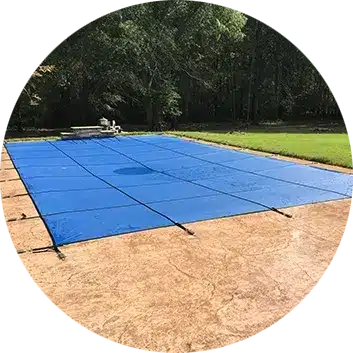Rectangular swimming pool covered with blue safety cover secured with anchors on concrete deck